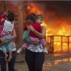 Residents of the Pinheirinho slum walk away from a fire set by other residents resisting police arrival to evict them in Sao Jose dos Campos