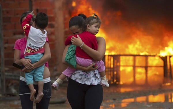 Residents of the Pinheirinho slum walk away from a fire set by other residents resisting police arrival to evict them in Sao Jose dos Campos