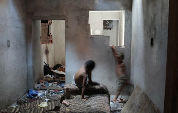 Crianças brincam dentro de suas casas repletas de entulho. (Foto: Reprodução/Shift)